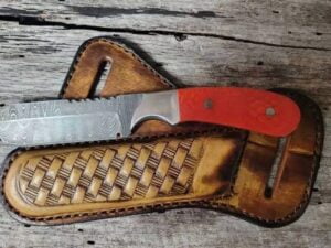 Damascus steel bull cutter knife with red tooled leather sheath.