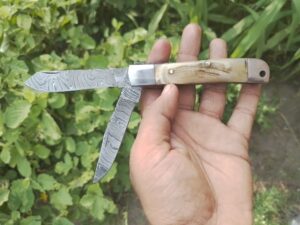 Double Blade Damascus Trapper Knife with ram horn handle and leather sheath.