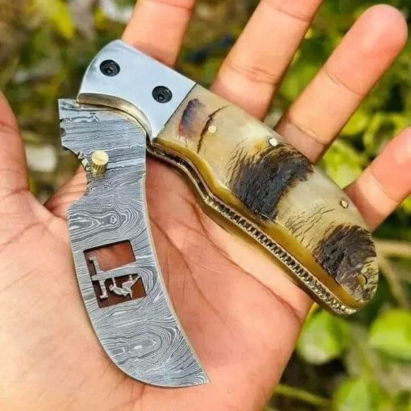 Damascus steel folding hawkbill knife with sheep horn handle and brass frame.