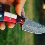 Hand-forged Damascus steel cowboy knife with Texas flag handle and handmade leather sheath.