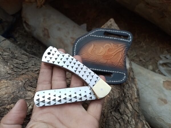 Hand-forged folding bull cutter knife made from a repurposed farrier's rasp, with brass bolsters and cross draw leather sheath.