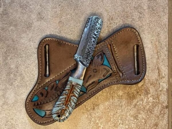 Damascus bull cutter knife with pine cone handle and pancake sheath.