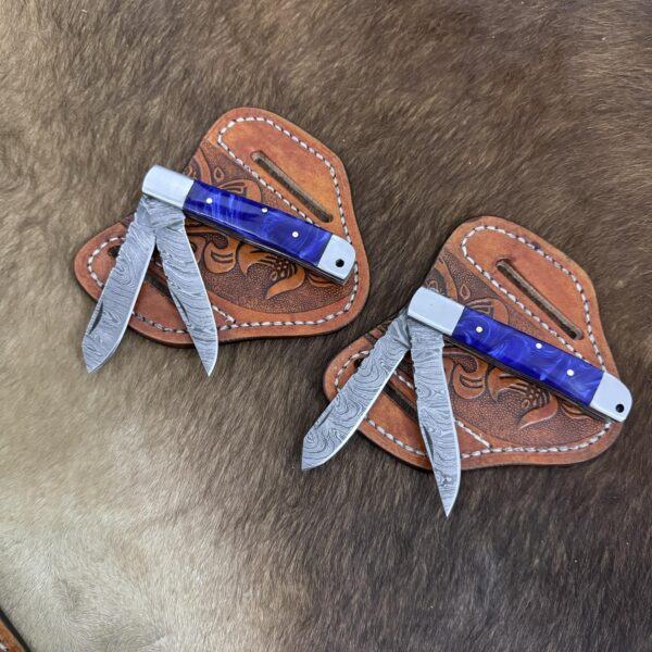 Custom Cowboy Knives (CCK) Damascus steel trapper knife set featuring two folding blades and a hand-stitched leather sheath.